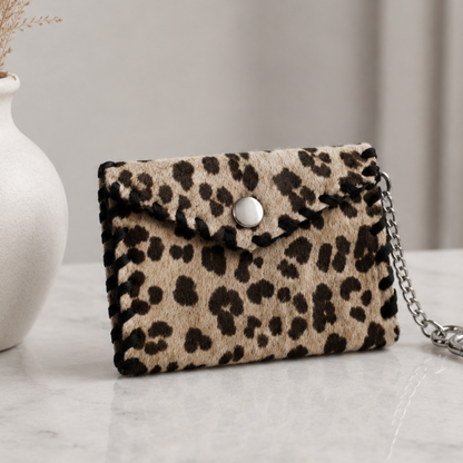 Monedero animal print confeccionado en cuero y pelo natural con detalle de costura artesanal negra.